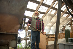 Luke Persons feeds woodchips in a pyrolysis machine — or kiln — to make biochar.
