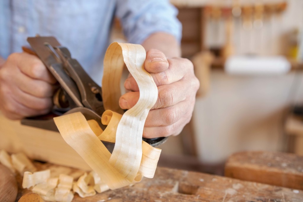 Charlie Shackleton hand planes a piece of wood in his workshop in Bridgewater. Photo by Erica Houskeeper.