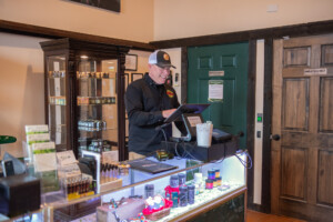 Jeremy Deschaine, general manager of Vermont Hempicurean in West Brattleboro, works the register at the company’s Vermont Bud Barn dispensary. Photo by Erica Houskeeper.