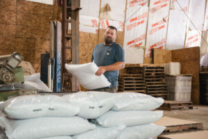 Anthony Ryea stacks bags of pellets at Vermont Natural Forest Products in Richford. Vermont Natural Wood Products provides every employee with free wood pellets, enough to heat their homes all winter. Photo by Erica Houskeeper.