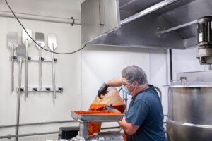 Corey Hodgdon makes maple sriracha at Butterfly Bakery. The maple syrup and chili peppers used in Butterfly Bakery products are grown within 200 miles of the facility. Photo by Erica Houskeeper.